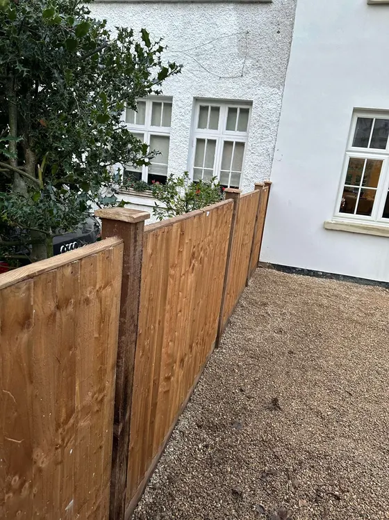 Closeboard fence along the side of a house over a gravel path