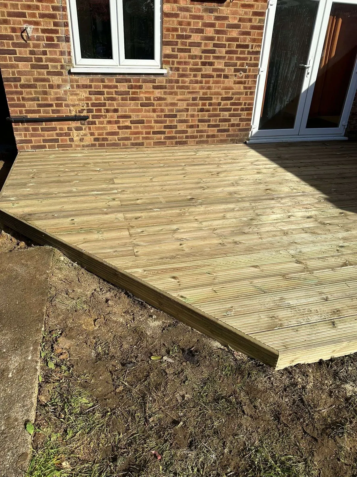 Timber deck platform at the back of a brick house