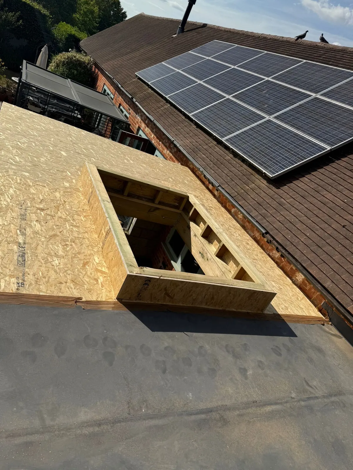 Flat roof with a rooflight kerb beside solar panels