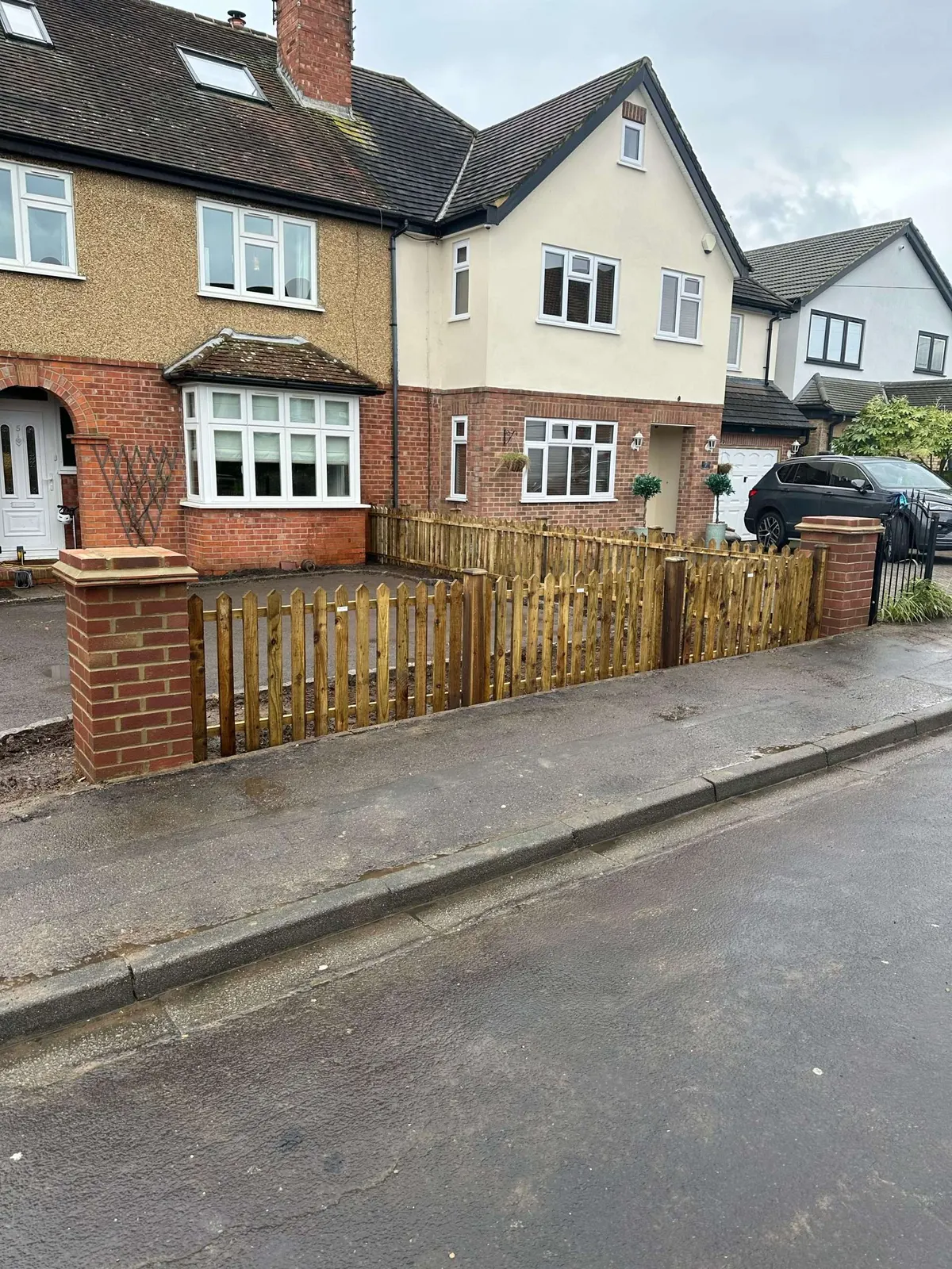 Low timber front boundary fence between brick piers on a residential street