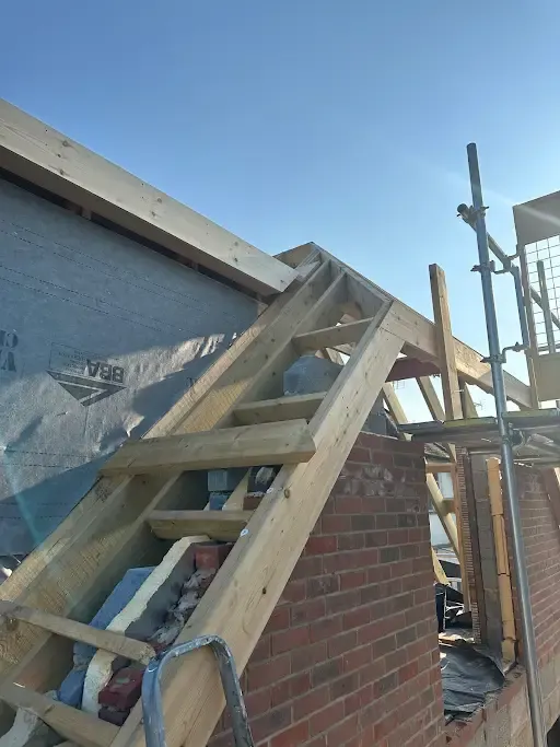 Gable roof framing on an extension with scaffold and ladder