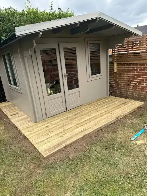 Finished grey garden room with deck in a fenced garden