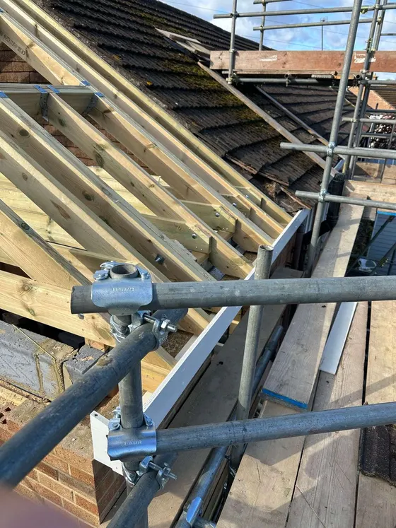Hand-cut roof rafters going up behind scaffold