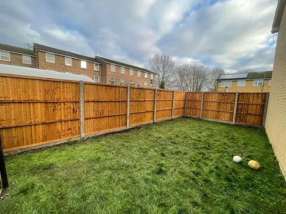 New panel fence with concrete posts and gravel boards around a lawned garden