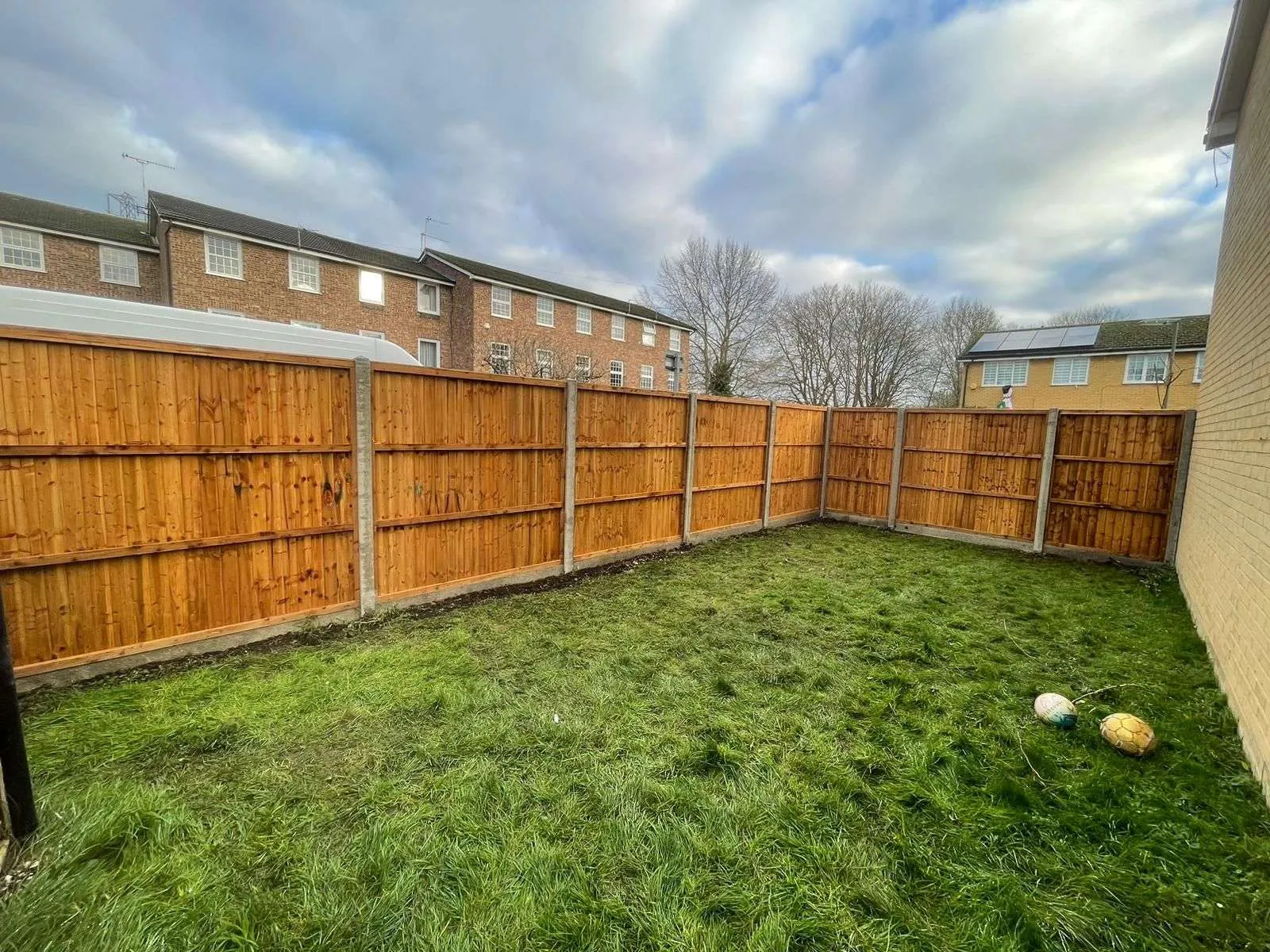 New panel fence with concrete posts and gravel boards around a lawned garden