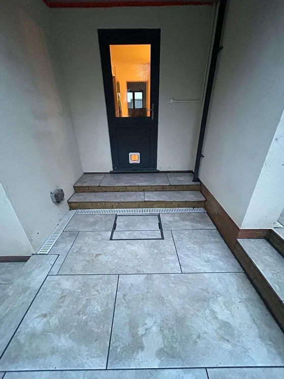Porcelain-tiled entrance with a step up to the door