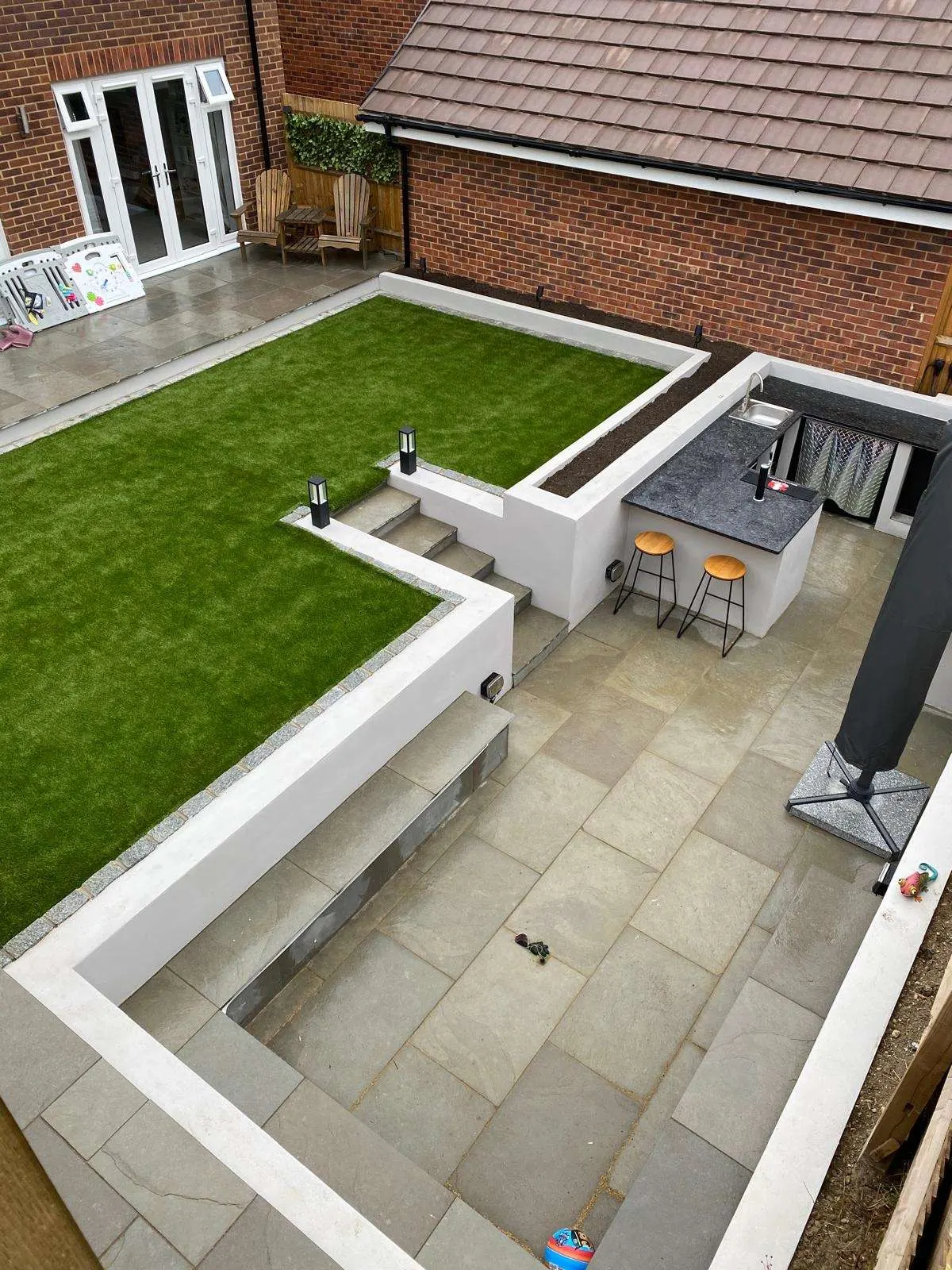 Porcelain patio with rendered raised beds and a raised lawn