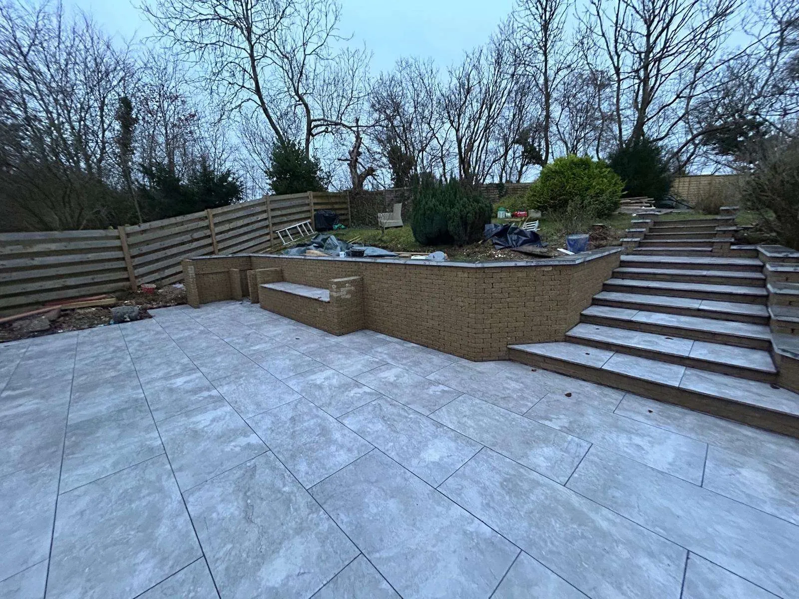 Large grey porcelain terrace with wide steps up to a raised garden