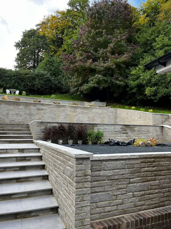 Stone-faced retaining walls and steps up a sloping garden