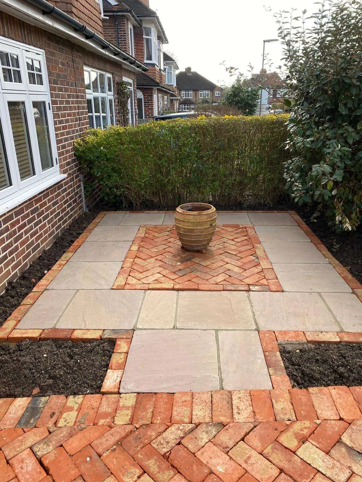 Sandstone front patio edged with herringbone brick