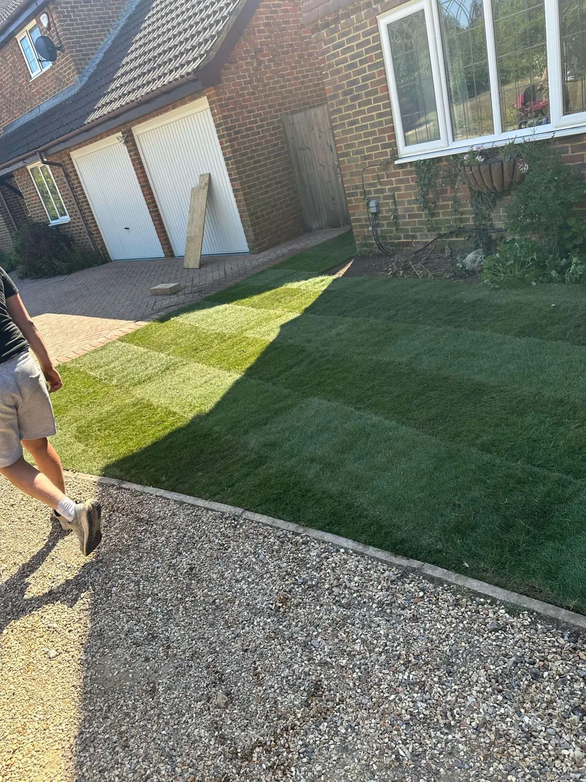 New turf rolled out in a front garden beside a gravel drive
